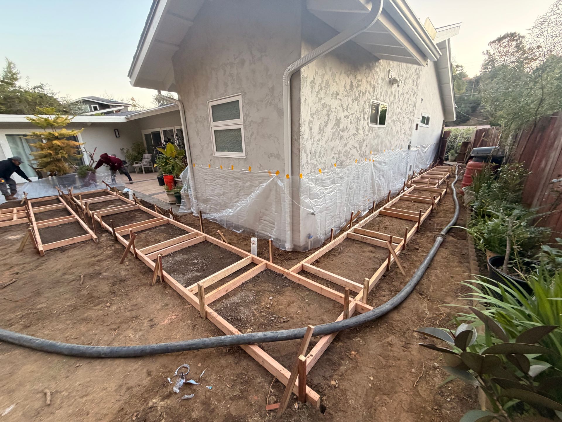 Man in work clothes uses a hammer to install a landscape stake in a garden.