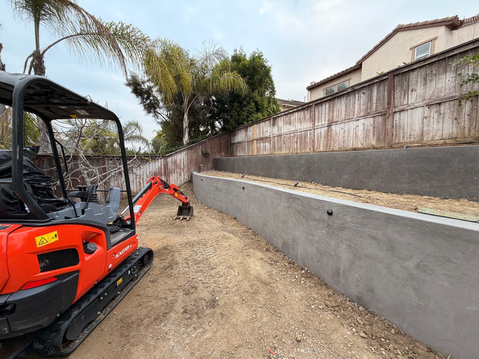 Man in work clothes uses a hammer to install a landscape stake in a garden.