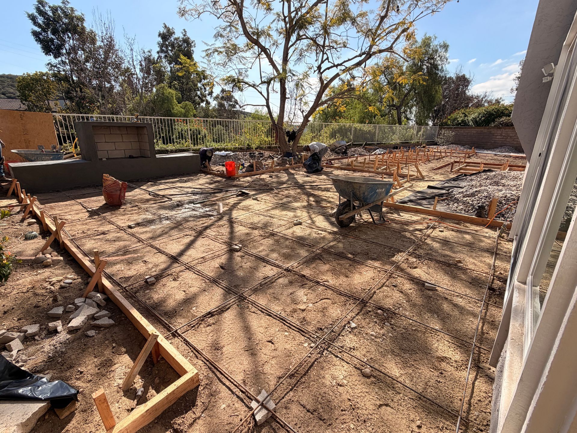Man operating an orange Kubota excavator in a backyard, digging into the earth.