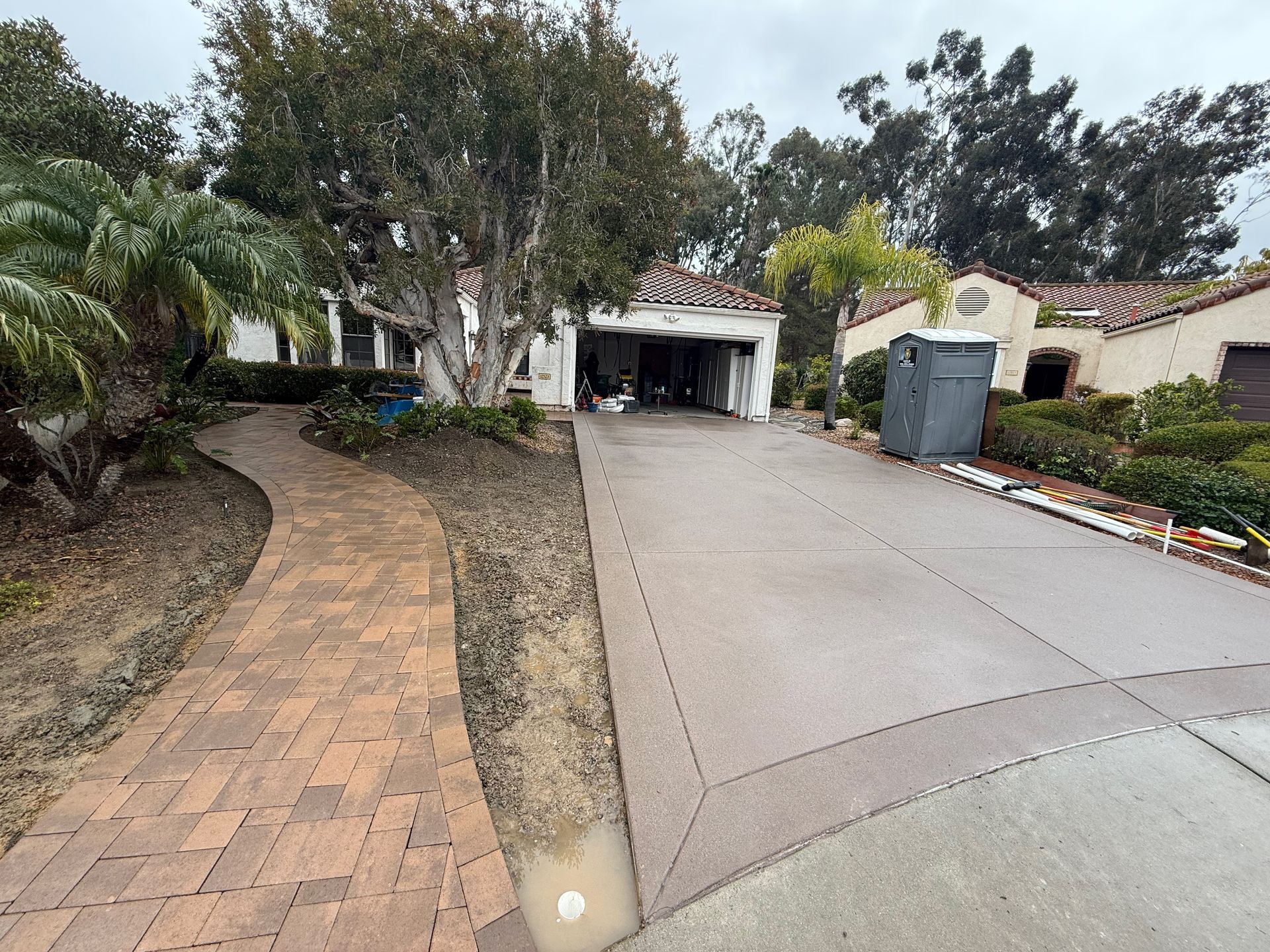 House exterior with brick walkway, driveway, and garage. Overcast sky.