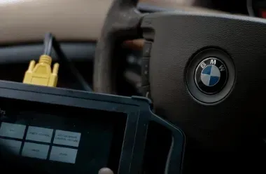 BMW steering wheel and diagnostic device with yellow cables in a car interior