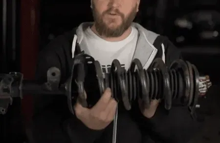 Person holding a large dumbbell in a dim gym, with a close-up of the weights and bar.