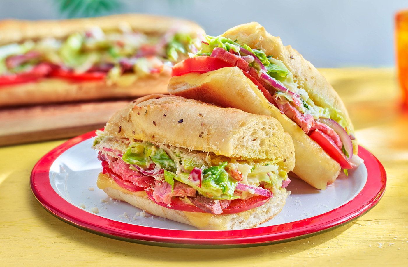 Two sub sandwiches are stacked on top of each other on a plate.