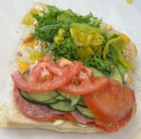 Two sub sandwiches are sitting on a wooden table.