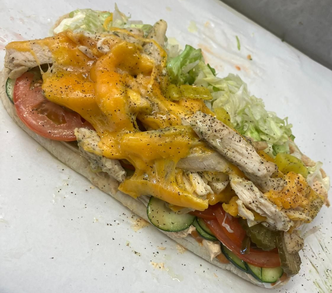 A sandwich is sitting on a wooden cutting board.