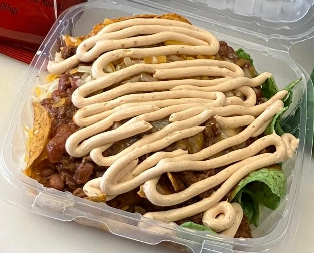 A sub sandwich with salami , cheese , lettuce and tomatoes on a wooden cutting board.