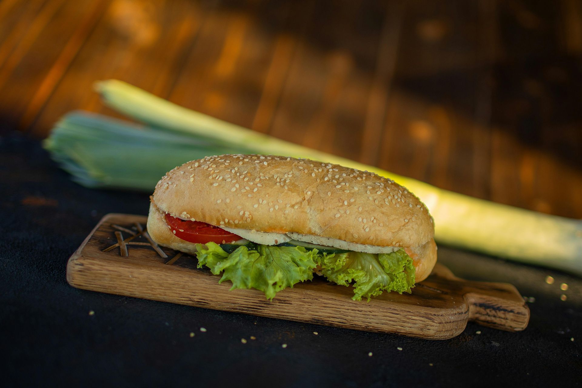 A sandwich is sitting on a wooden cutting board.