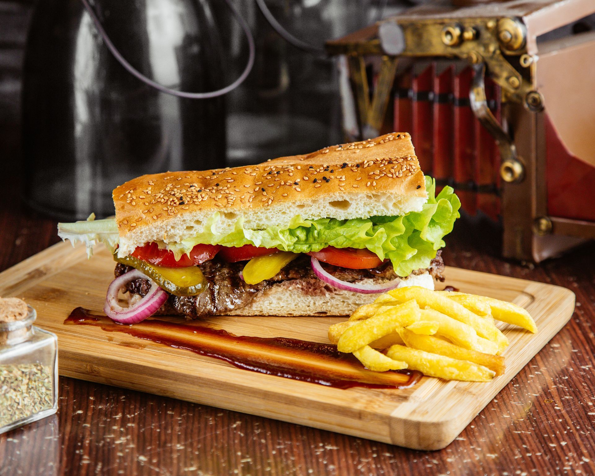 A sub sandwich with french fries on a wooden cutting board.