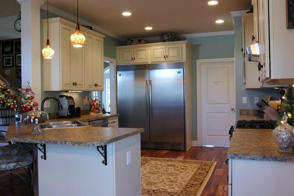 Kitchen with cream cabinets, stainless steel refrigerator, and granite countertops.