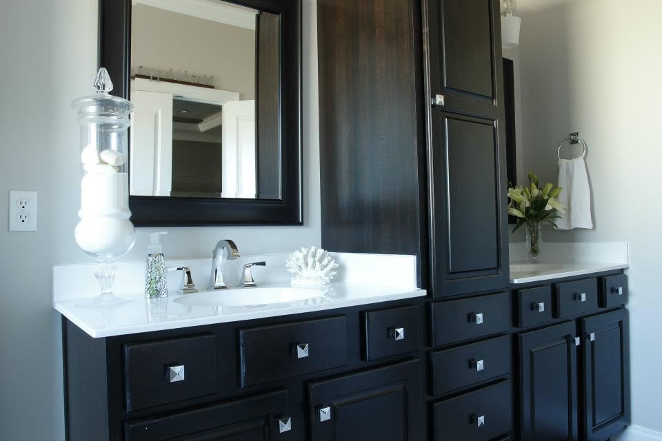 Bathroom with dark cabinets, white countertop, and large mirror.