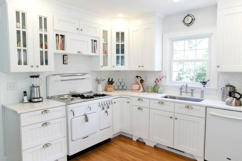 White kitchen with cabinets, stove, sink, and window.