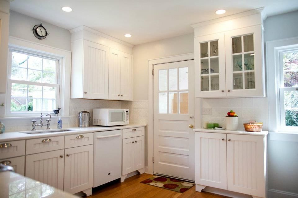 White kitchen with cabinets, sink, microwave, and door.