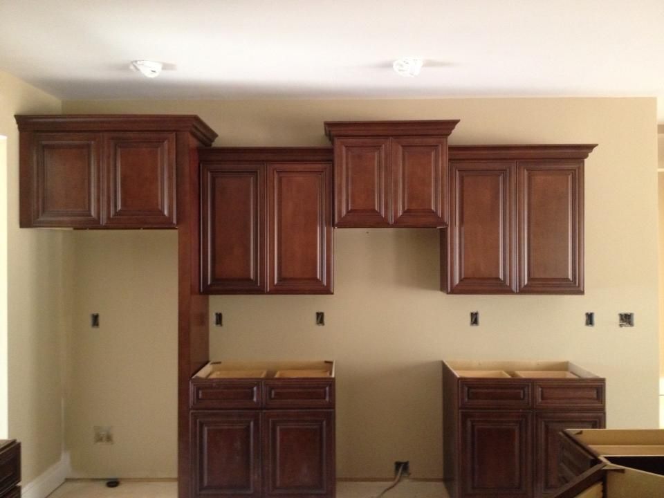 Brown kitchen cabinets installed on tan walls.