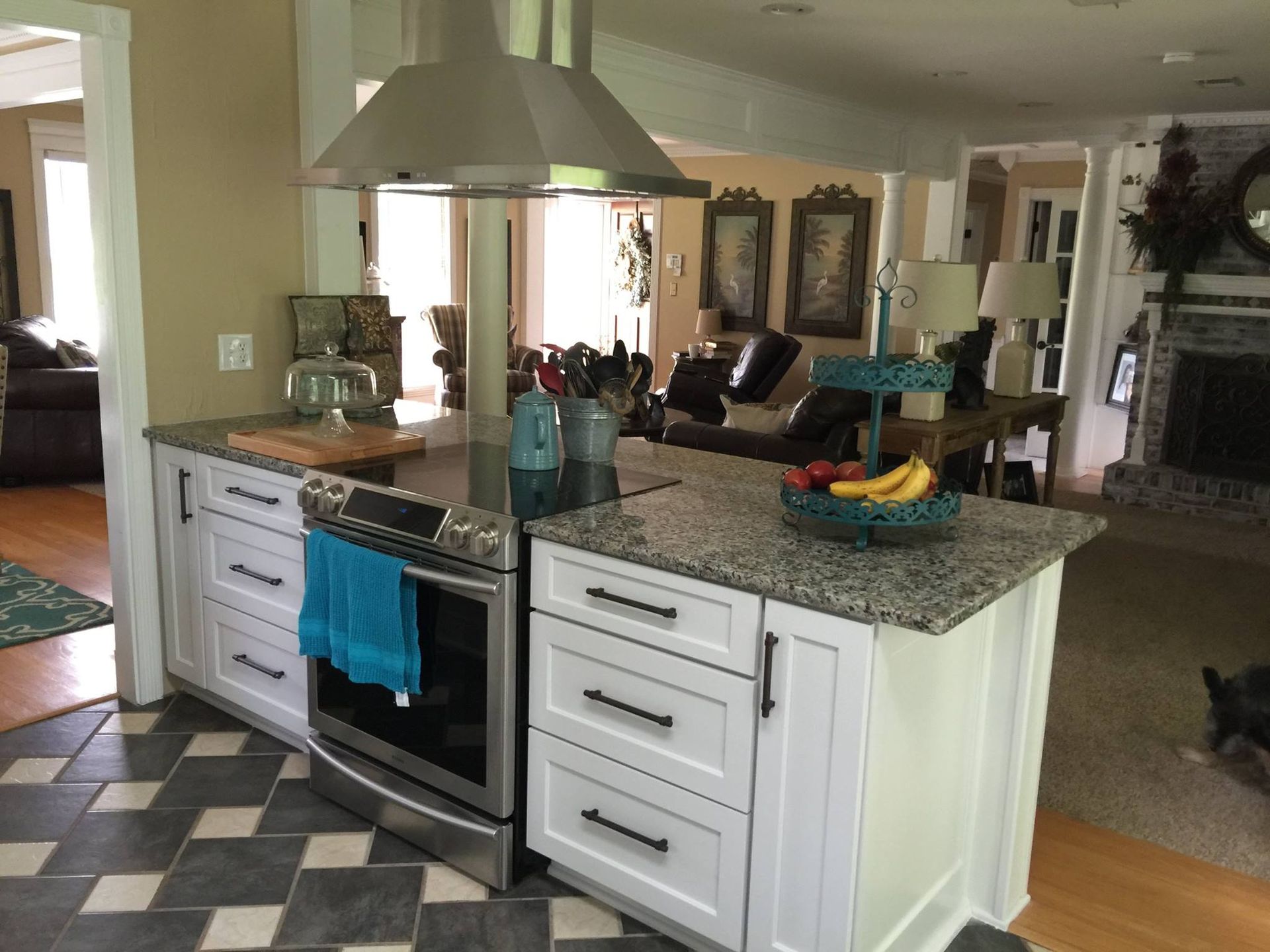 Kitchen with white cabinets, gray countertops, and stainless steel appliances. Black and gray checkered floor.