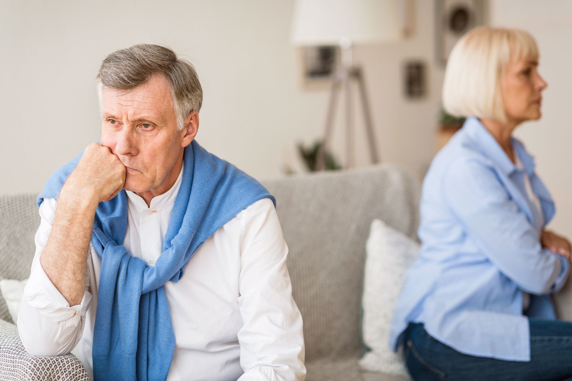 A man and a woman are sitting on a couch with their backs to each other.