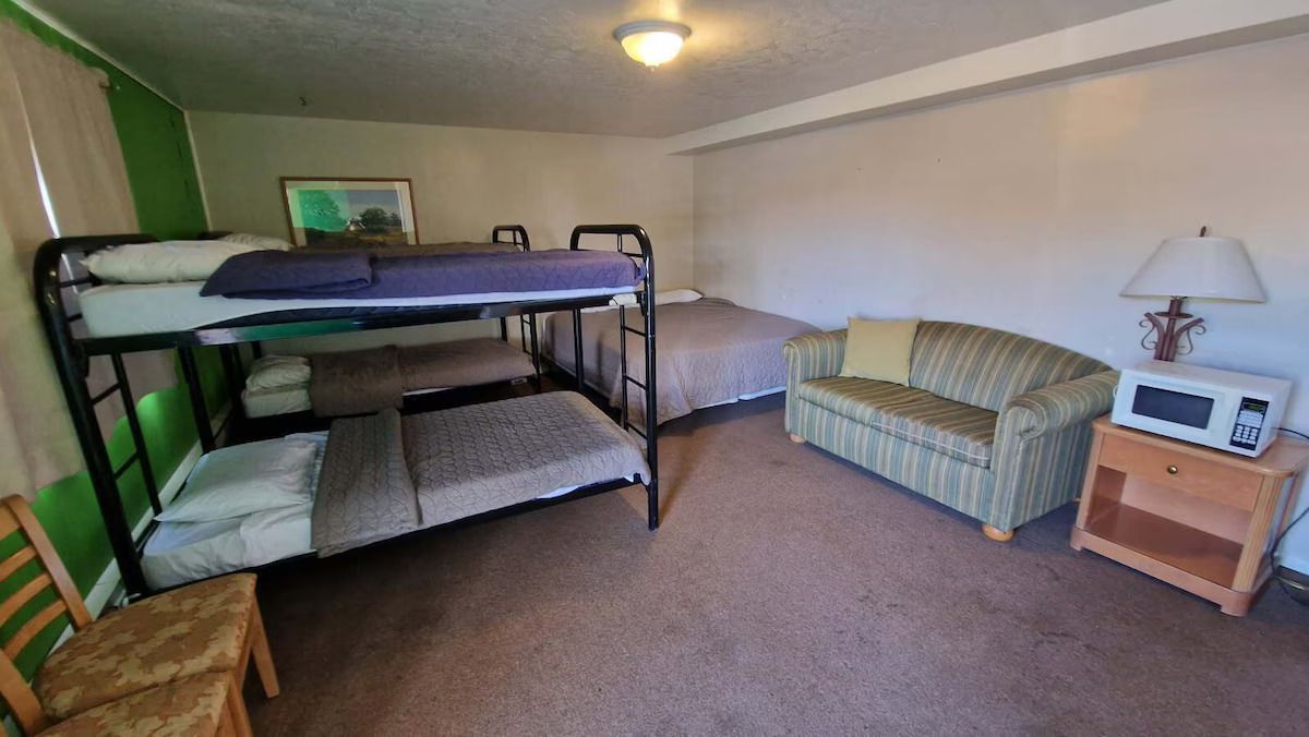 A room with bunk beds , a couch , and a microwave.