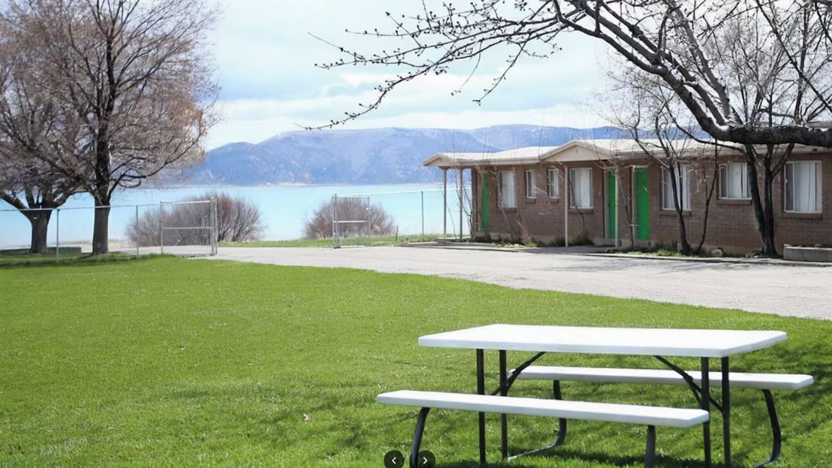 A picnic table is sitting in the grass in front of a house.