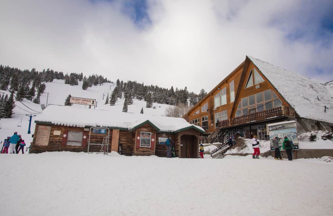 A group of people are standing in front of a snow covered building.