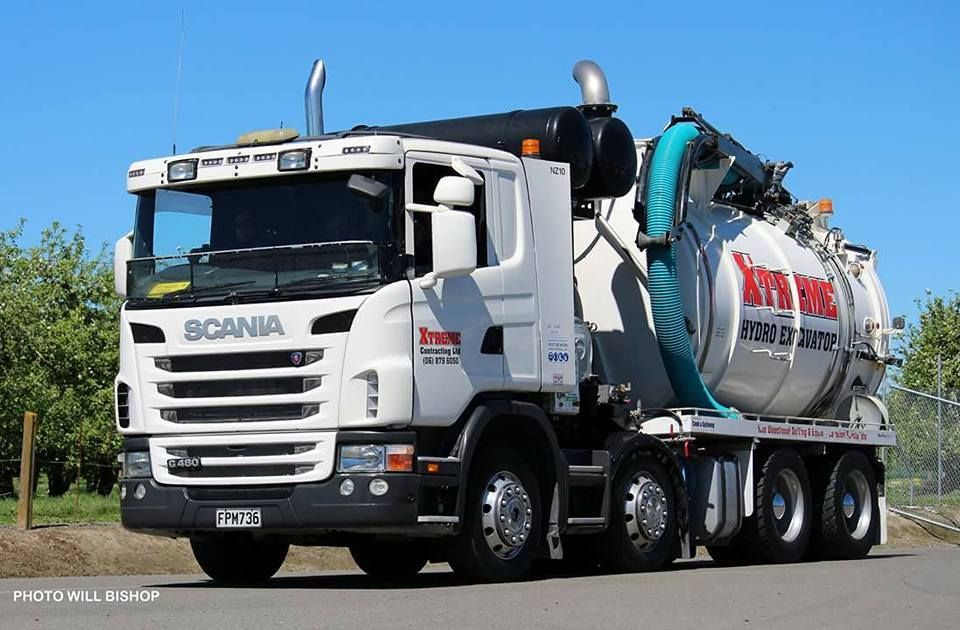 A white scania vacuum truck is parked on the side of the road