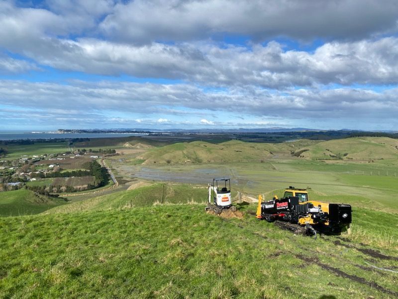 A couple of tractors are sitting on top of a grassy hill.