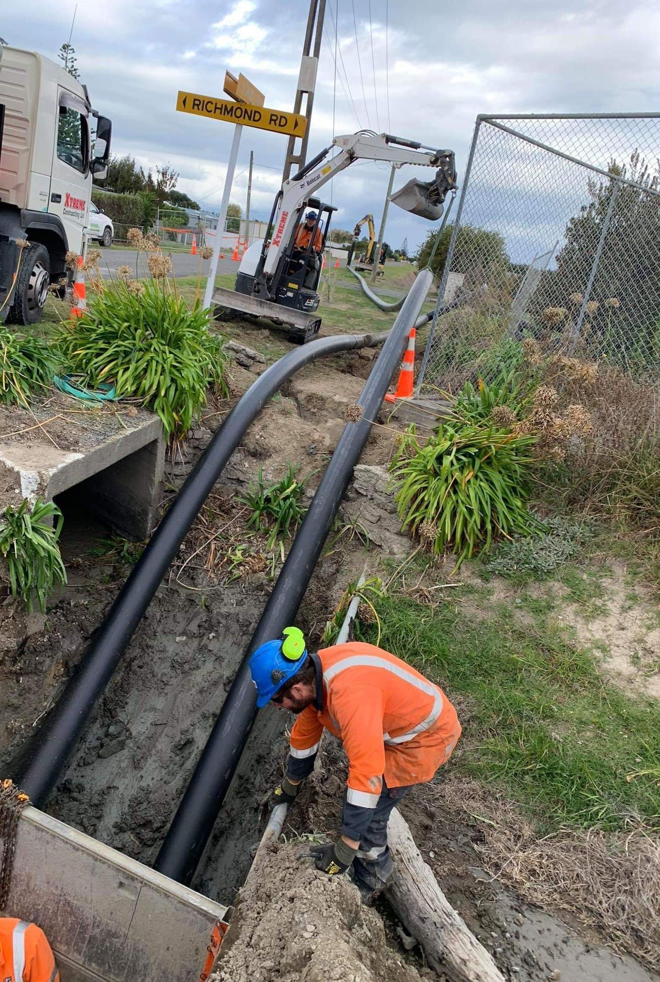 A man is working on a pipe in the dirt next to a truck.