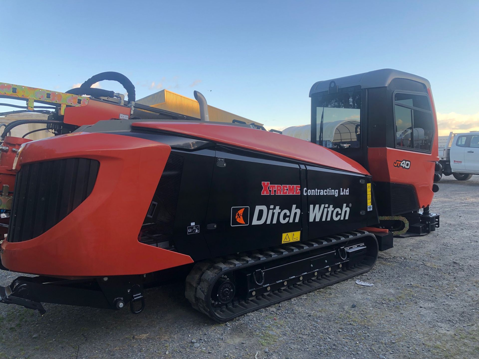 A red and black ditch witch machine is parked in a gravel lot.