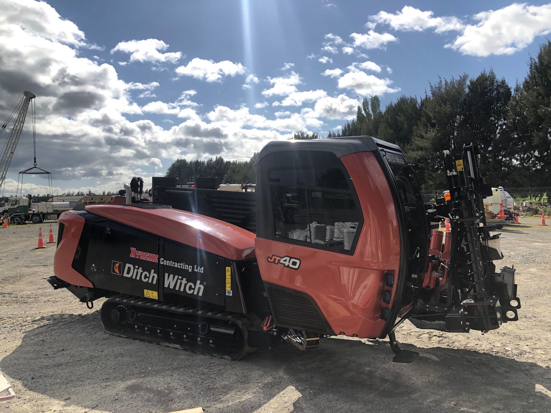 A red and black machine is parked in a gravel lot.