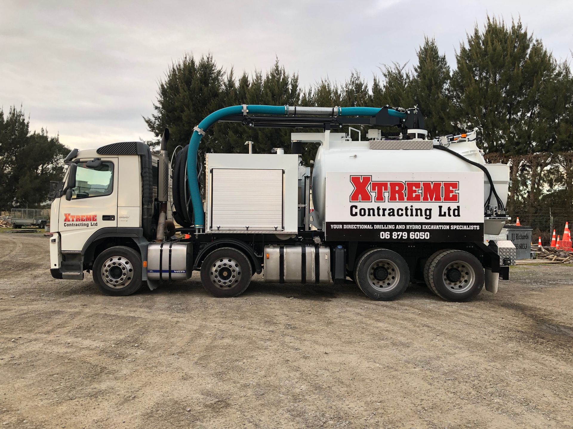 A vacuum truck from xtreme contracting ltd is parked in a dirt lot.