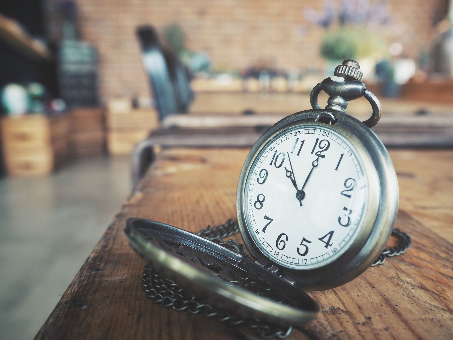 A pocket watch is sitting on a wooden table.