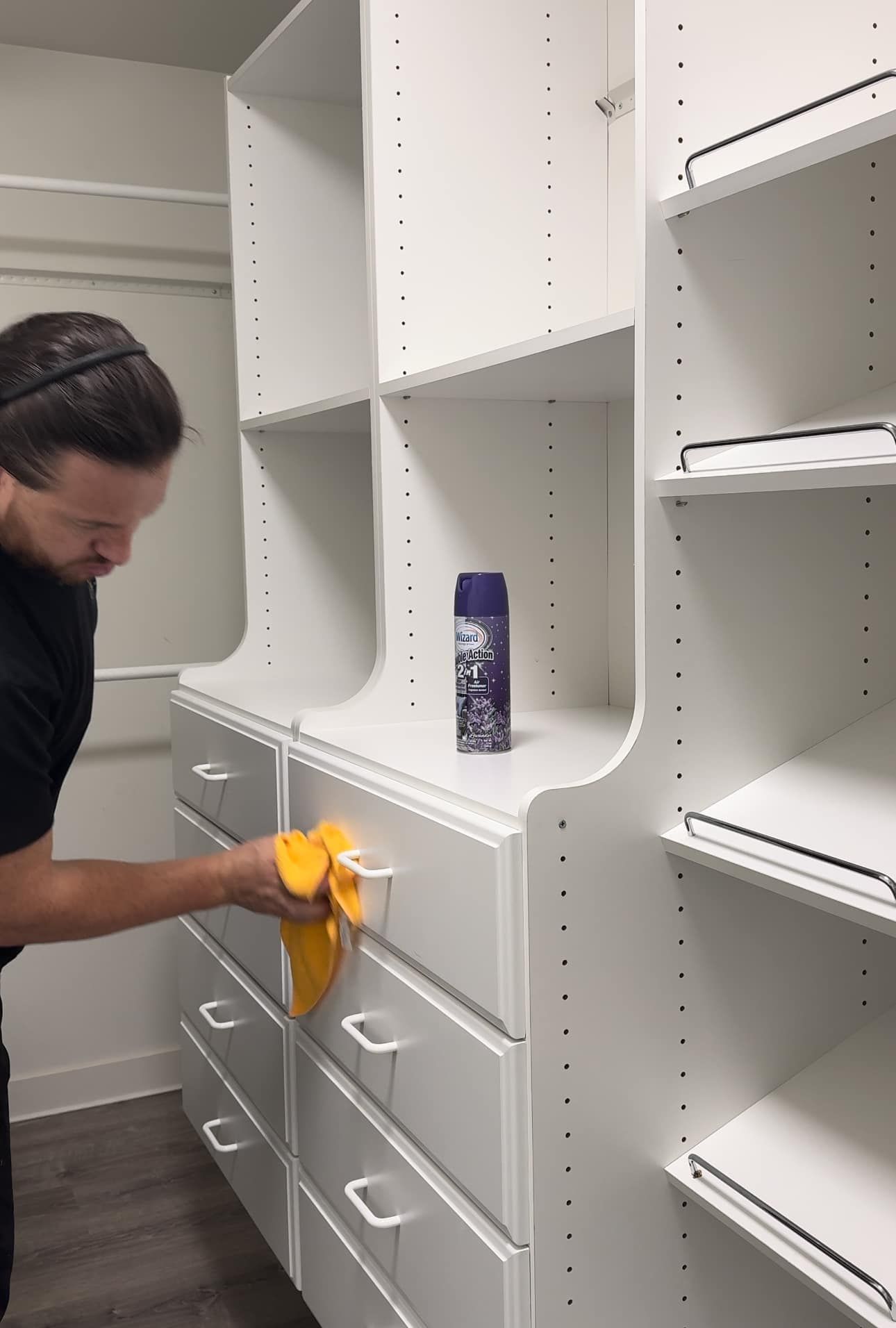 A man is cleaning a closet with a cloth.