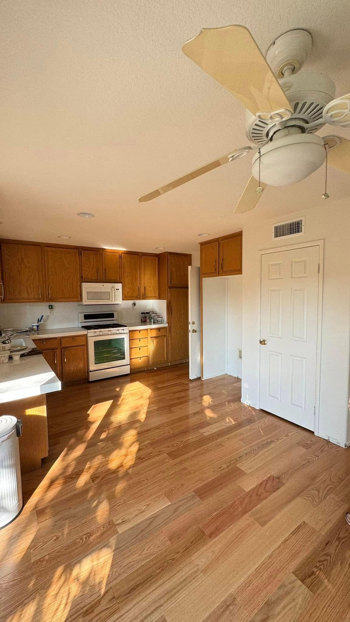 A kitchen with hardwood floors and a ceiling fan