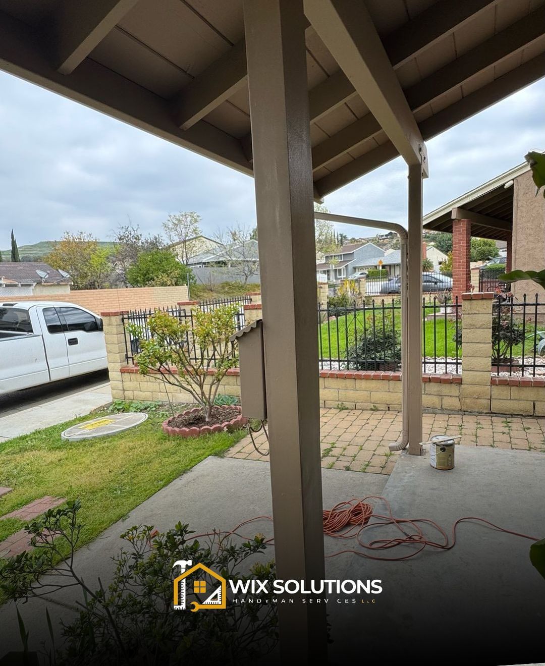 A white truck is parked under a covered porch.