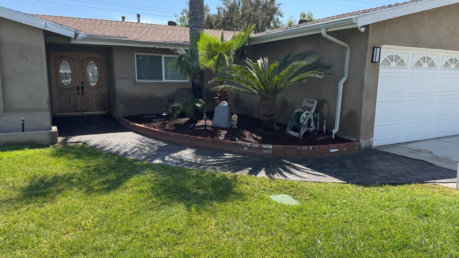 A house with a white garage door and a palm tree in front of it.