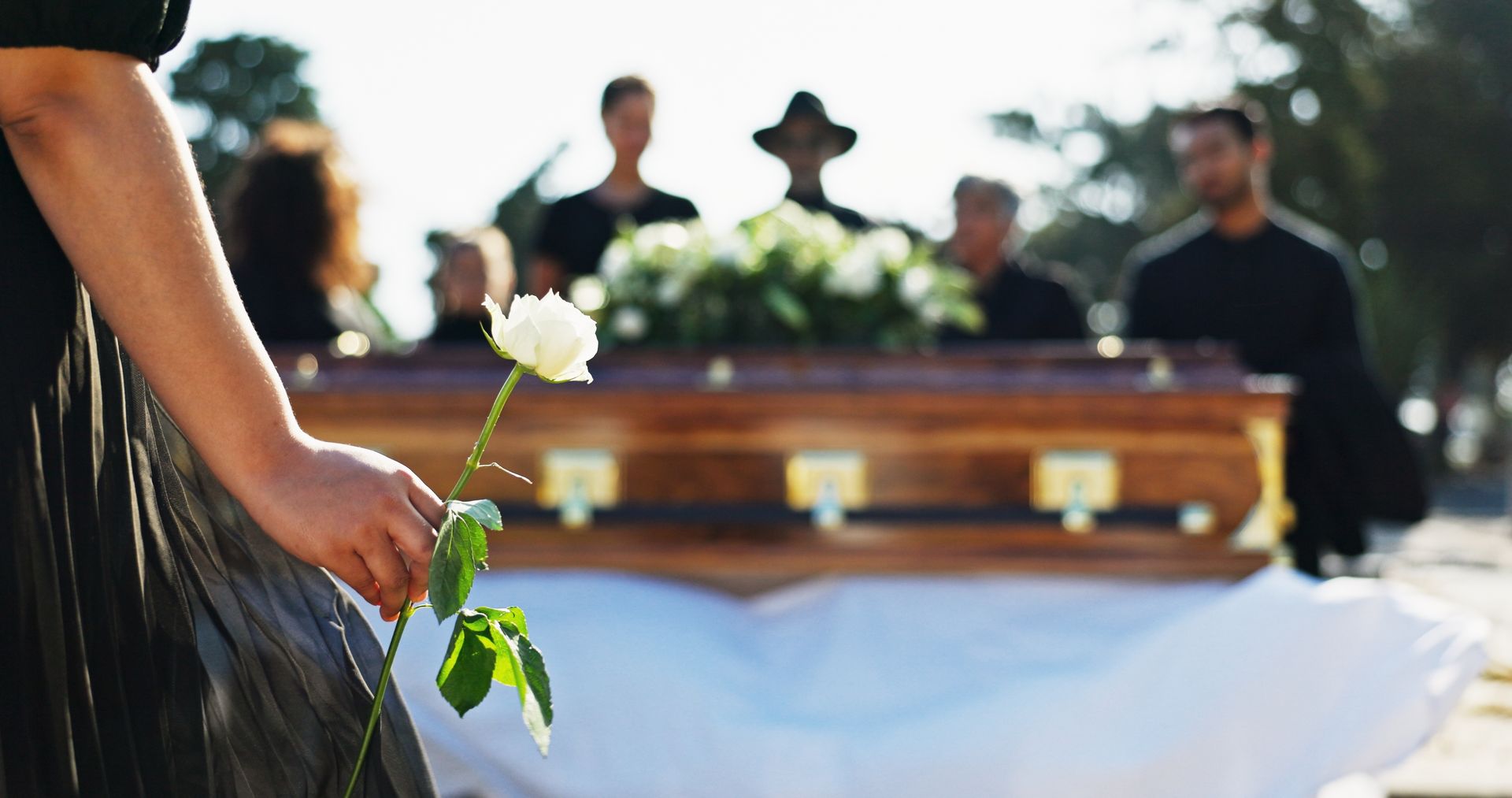 A woman in a black dress is holding a white flower in her hands.