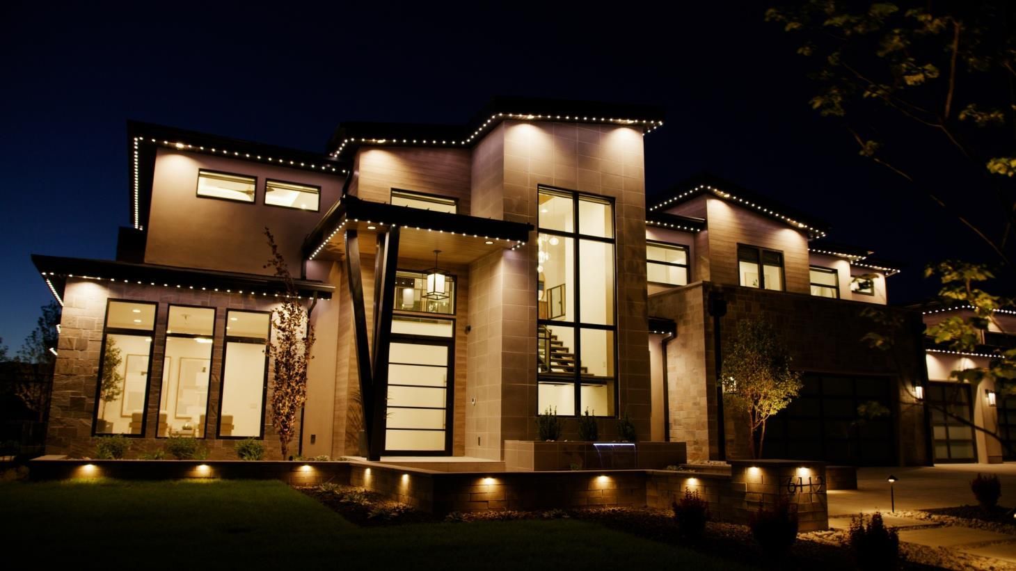 Electrician connecting wires to a ceiling light fixture, wearing gloves. Tools and wires visible.