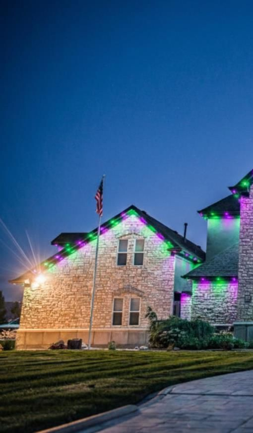 Electrician working on a wall outlet, wearing red gloves and a tool belt. A multimeter and safety helmet are nearby.