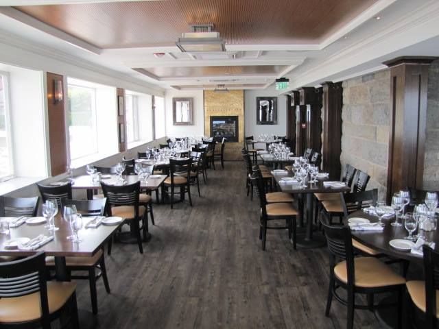 A long dining room with tables and chairs and a fireplace