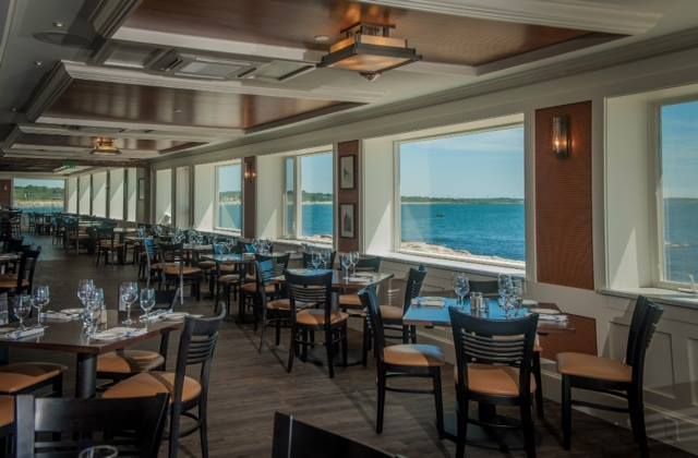 A restaurant with tables and chairs and a view of the ocean