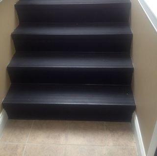 A set of black stairs leading up to a tiled floor.