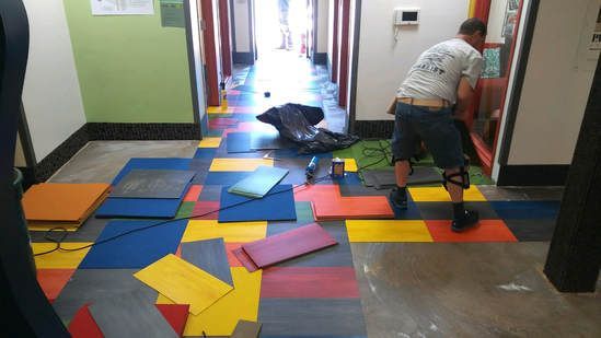 A man is working on a colorful floor in a hallway.