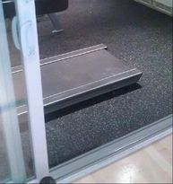 A treadmill is sitting in a gym next to a sliding glass door.