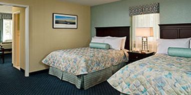 A hotel room with two beds and a picture on the wall.