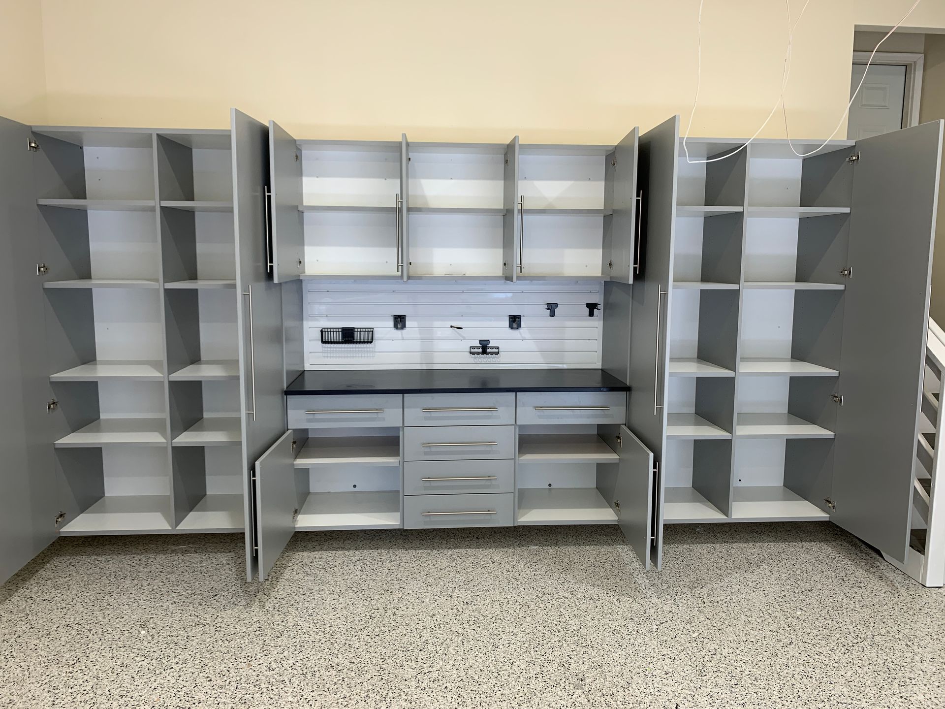 Grey walk-in closet with desk area. Includes hanging clothes, shelves, and a chair.
