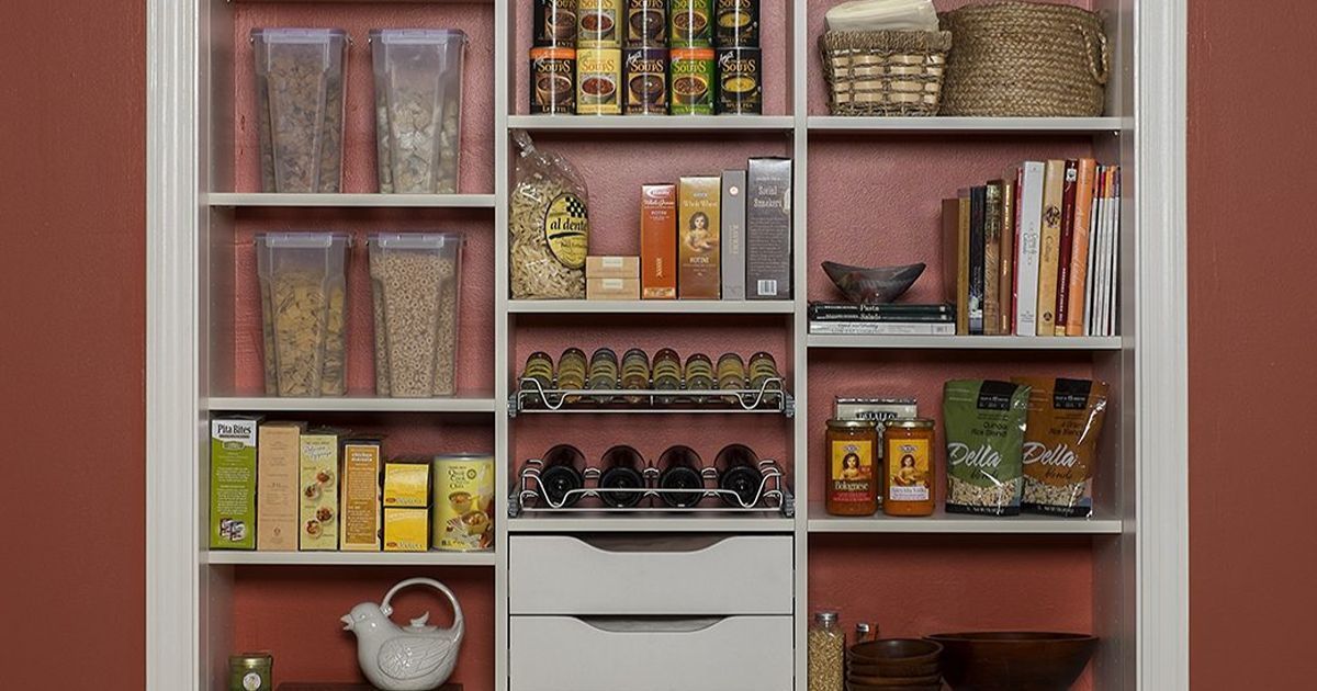 White pantry shelves with organized food items against a red wall.