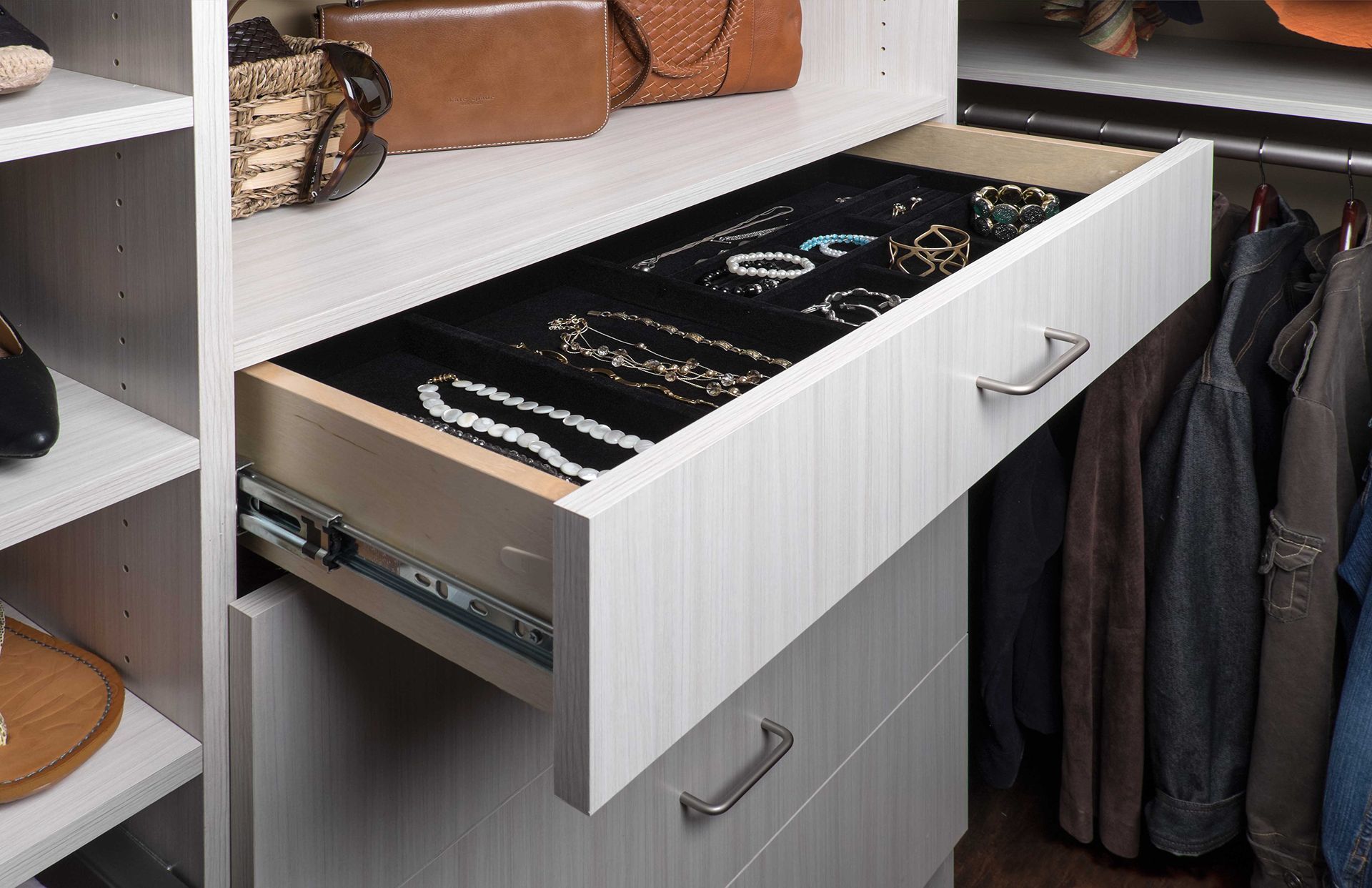 Open closet drawer with jewelry organized on black felt.