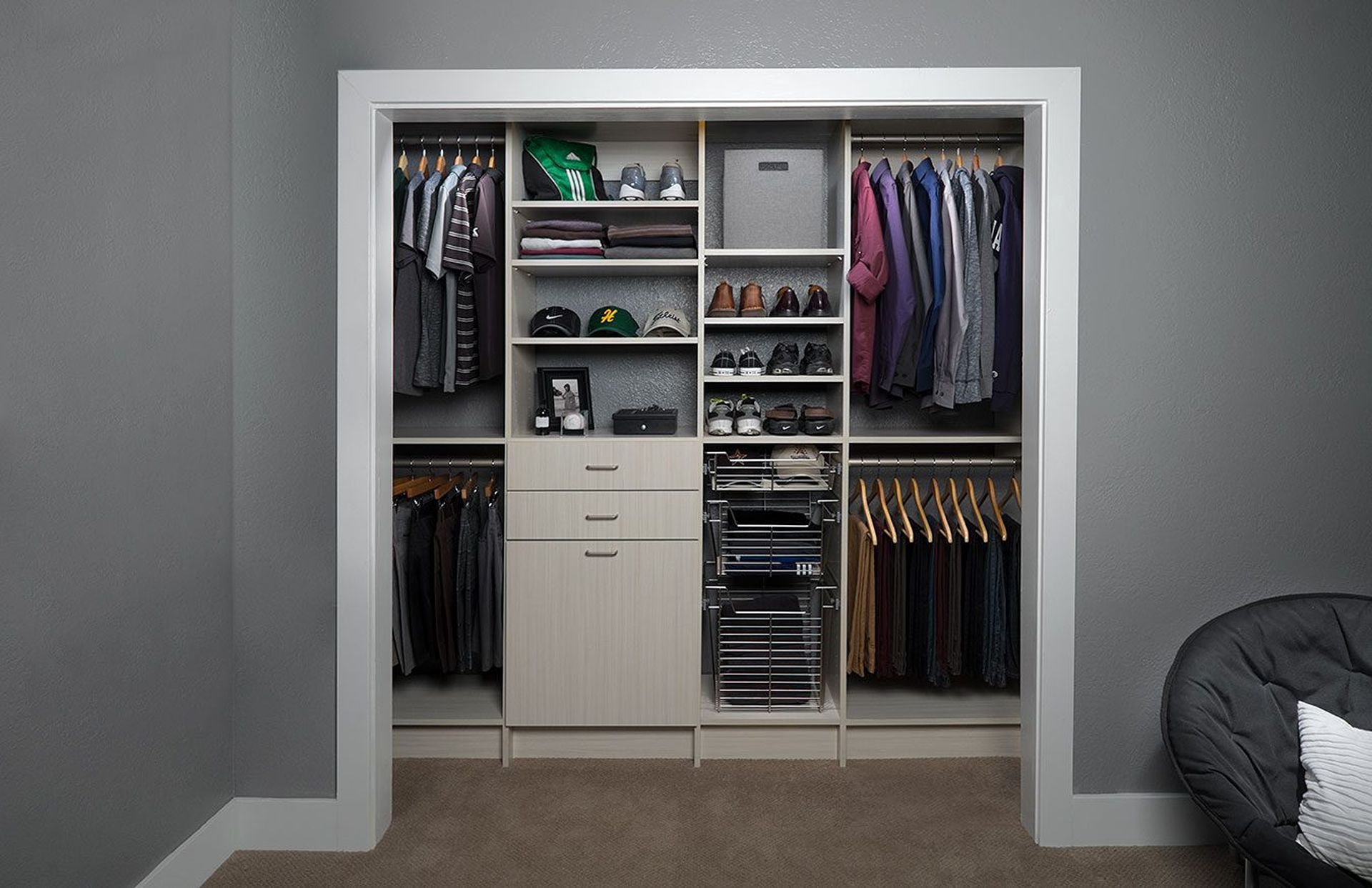 Open closet with clothes, shelves, drawers, and shoes in a gray bedroom.