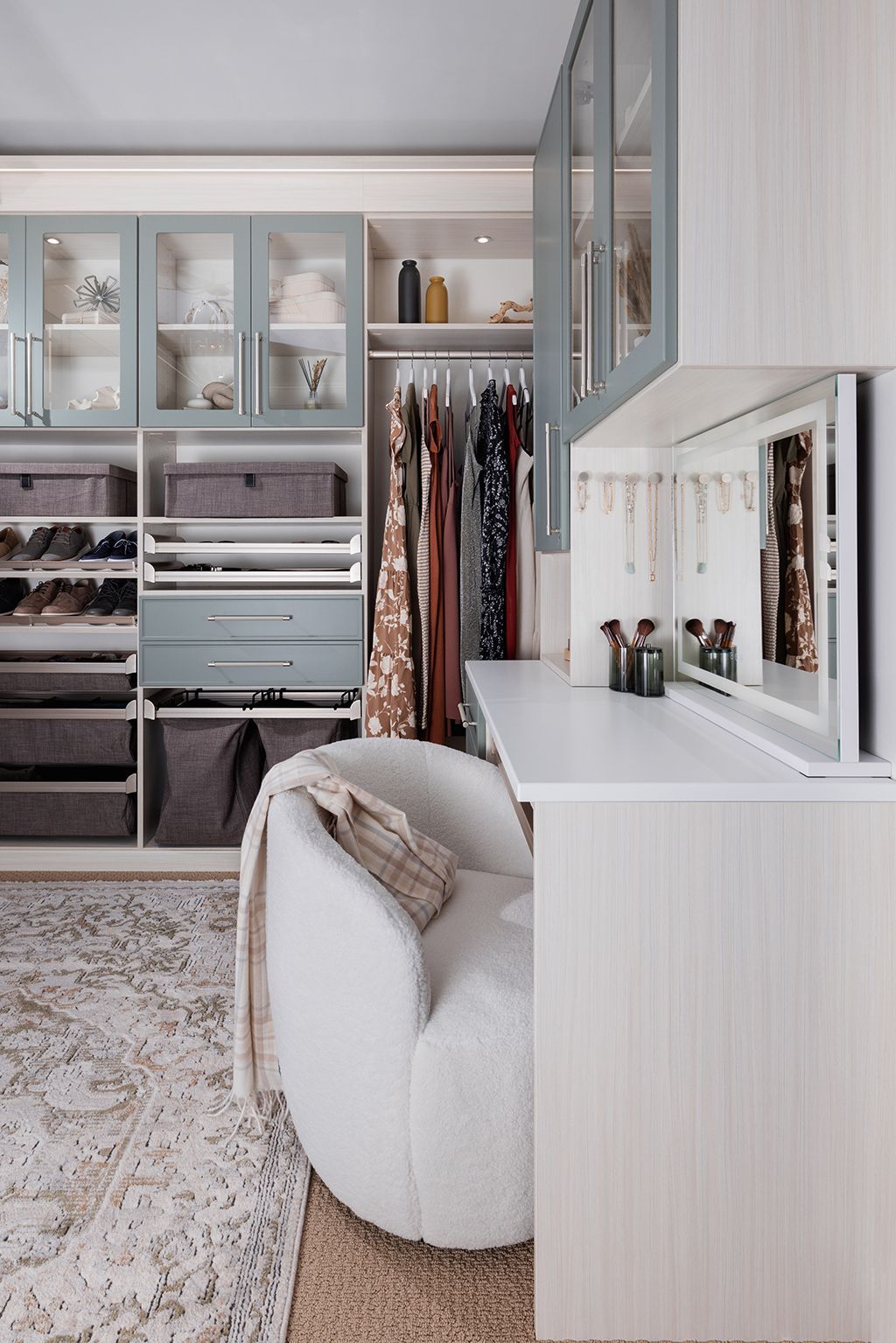 Grey walk-in closet with desk area. Includes hanging clothes, shelves, and a chair.