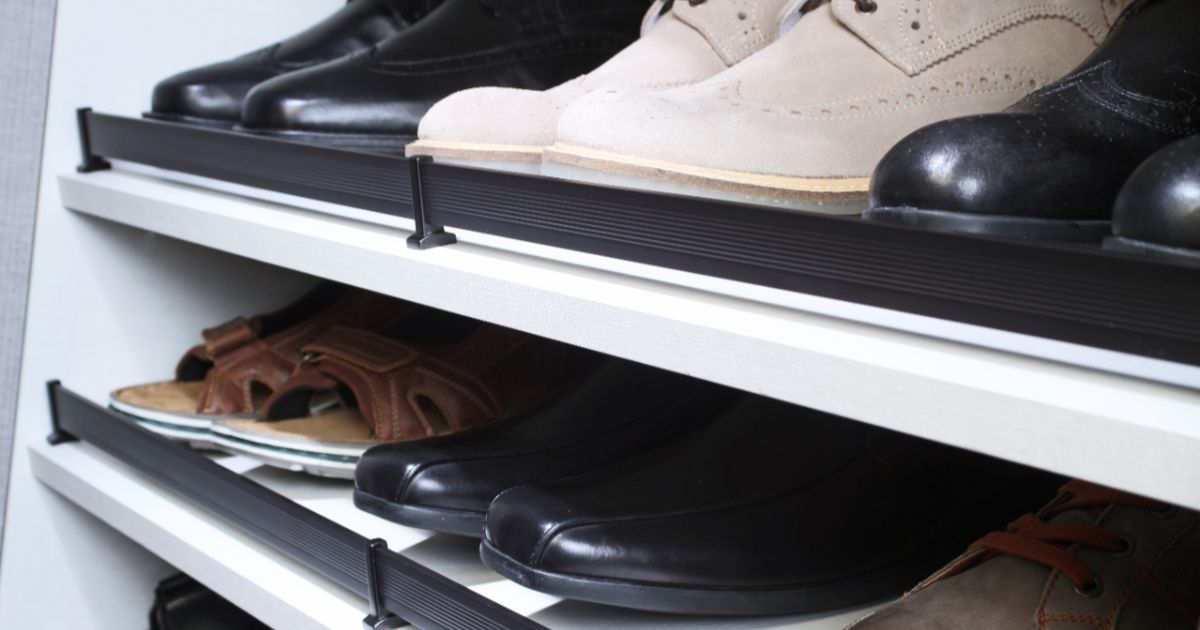 Shoes lined up on white metal shelves in a closet, including black, white, and brown pairs