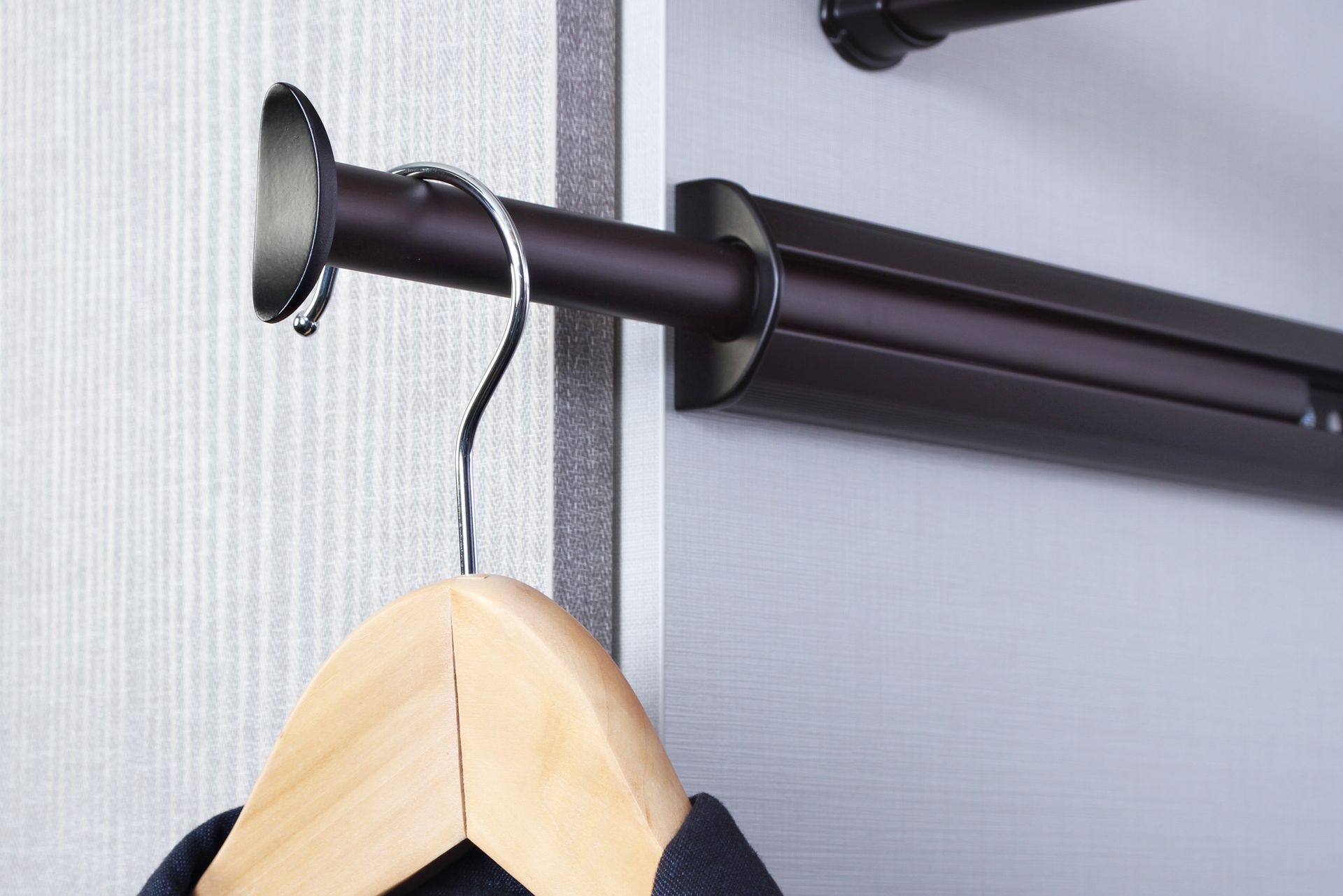 Black wall-mounted clothing rod with a wooden hanger hanging on it
