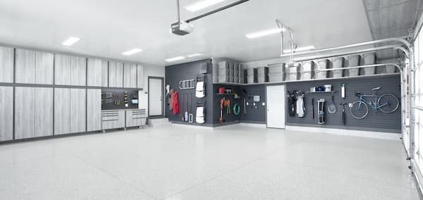Bright industrial garage with white floors, metal cabinets, and wall-mounted tools and bikes